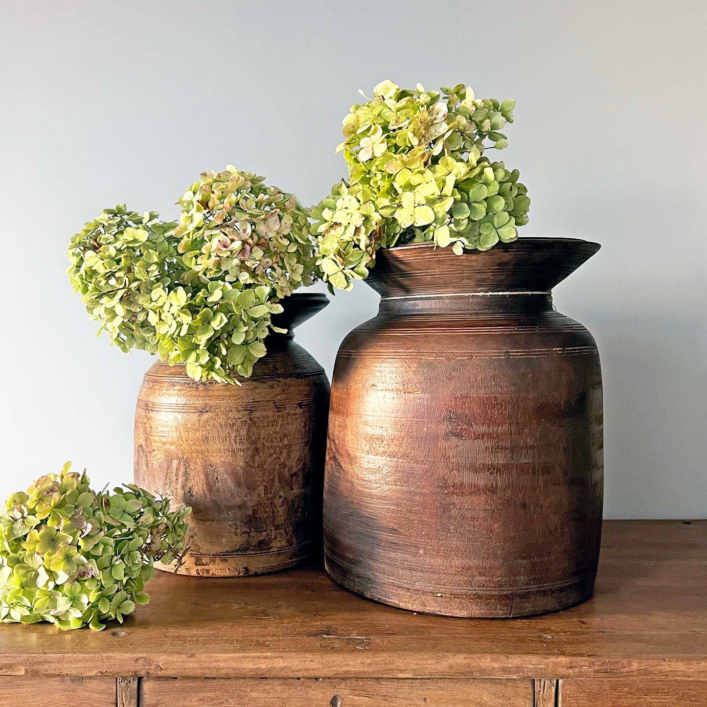 A photo of a two solid teak handcaved pots with hydrangeas for the House McGrath Luxury Gift List